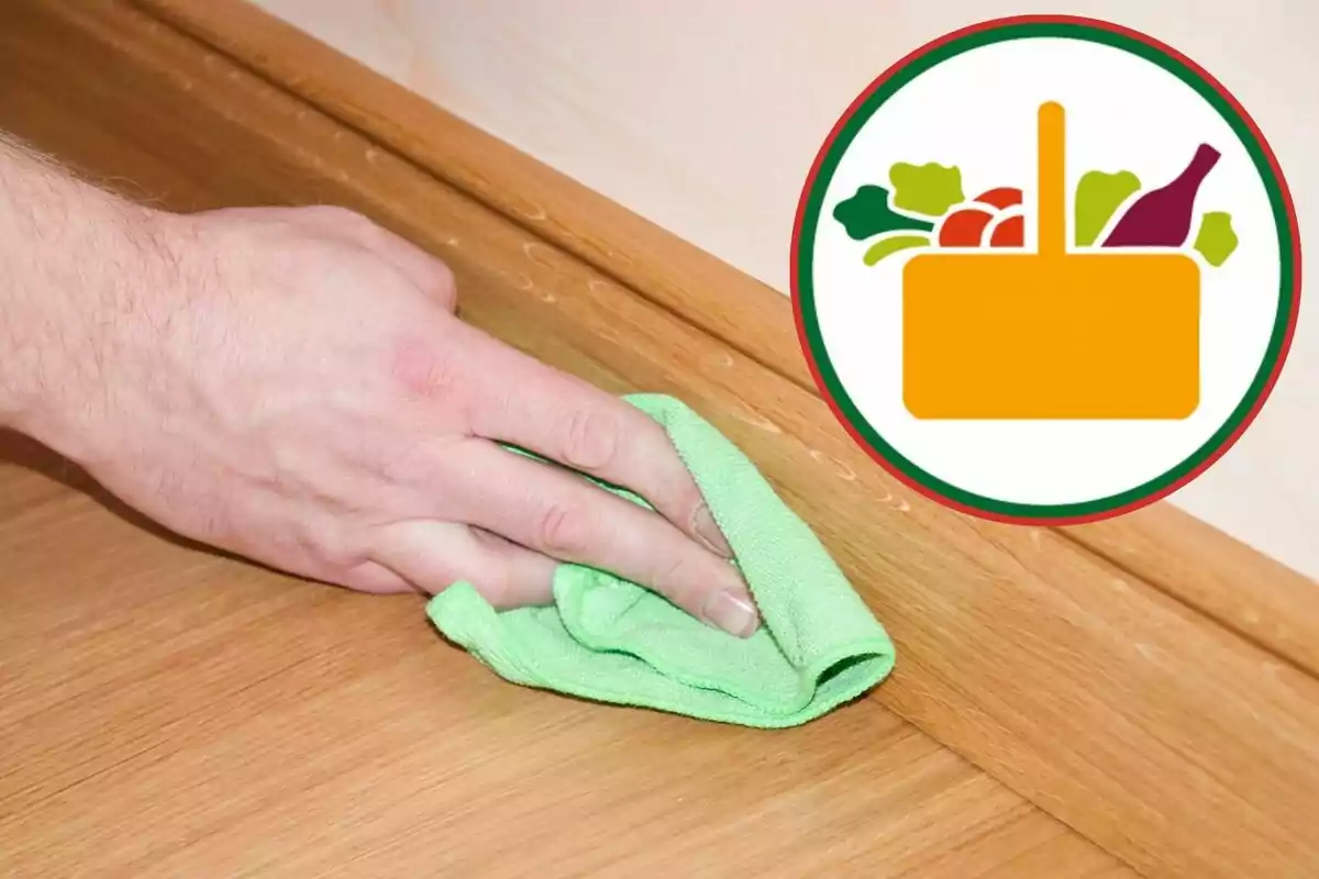 Mano limpiando una superficie de madera con un trapo verde y un icono de canasta de compras con alimentos en la esquina superior derecha Mano limpiando una superficie de madera con un trapo verde y un icono de canasta de compras con alimentos en la esquina superior derecha