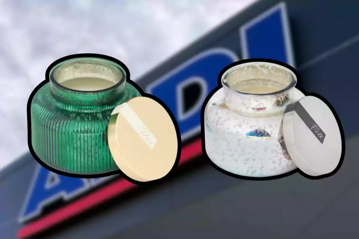 Dos velas aromáticas en frascos decorativos con tapa, una verde y otra blanca, sobre un fondo desenfocado de un letrero de tienda Dos velas aromáticas en frascos decorativos con tapa, una verde y otra blanca, sobre un fondo desenfocado de un letrero de tienda