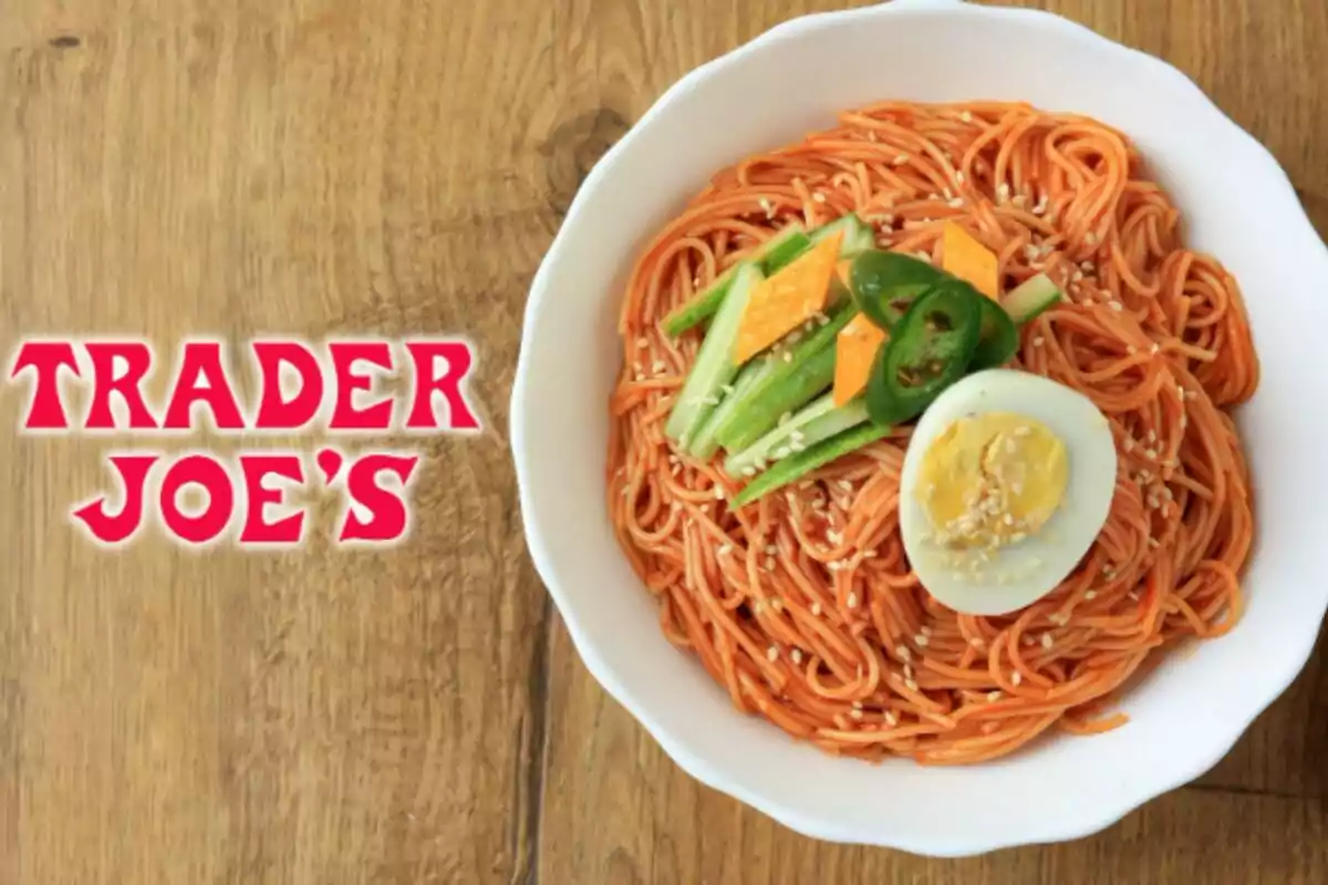 Plate of noodles with red sauce, boiled egg, cucumber, jalapeño, and sesame seeds—which is bibim-guksu, a typical Korean dish—next to the Trader Joe's logo on a wooden table. Plate of noodles with red sauce, boiled egg, cucumber, jalapeño, and sesame seeds—which is bibim-guksu, a typical Korean dish—next to the Trader Joe's logo on a wooden table.