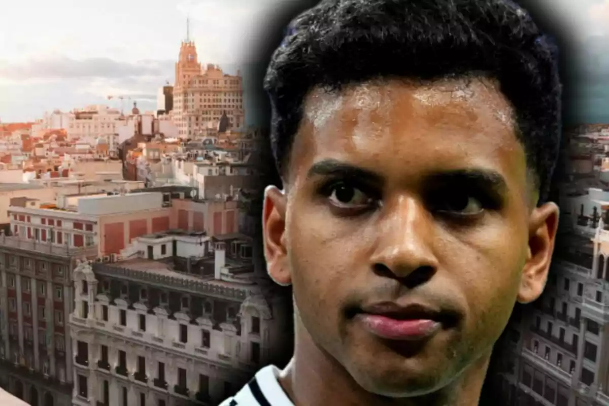 Close-up of Rodrygo Goes with a serious expression against a backdrop of iconic buildings in a European city, which is Madrid.