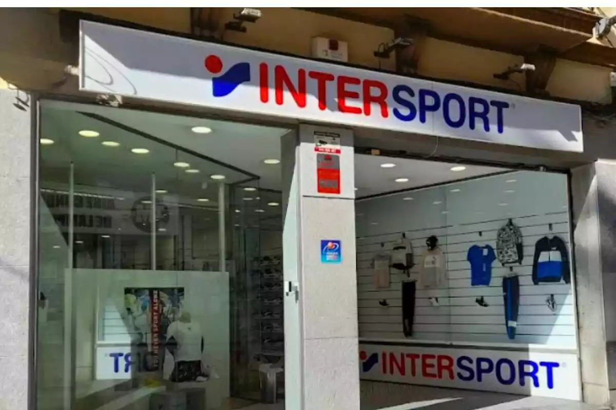 Fachada de una tienda Intersport con ropa deportiva exhibida en el escaparate y letrero grande en la entrada Fachada de una tienda Intersport con ropa deportiva exhibida en el escaparate y letrero grande en la entrada