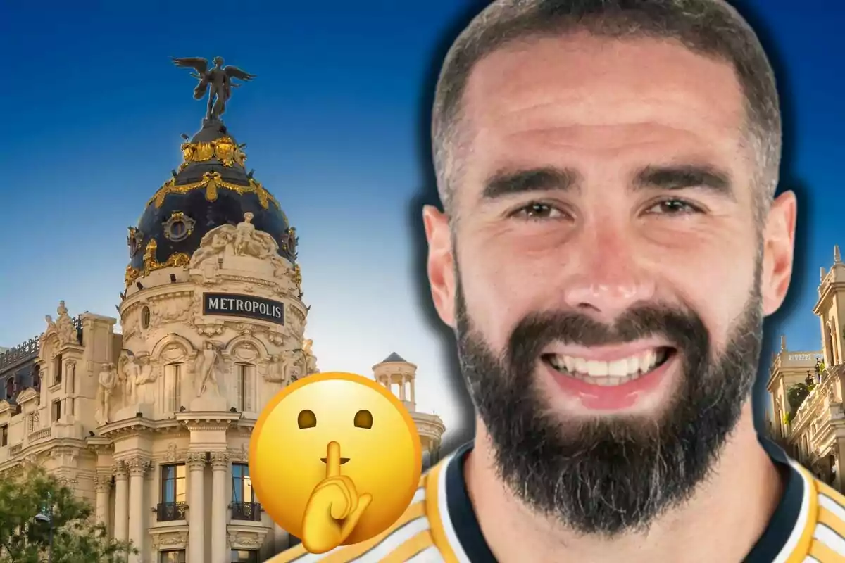 Dani Carvajal smiling in the foreground with a beard and a sports jersey, a shushing emoji, and the Metropolis building of Madrid in the background under a blue sky