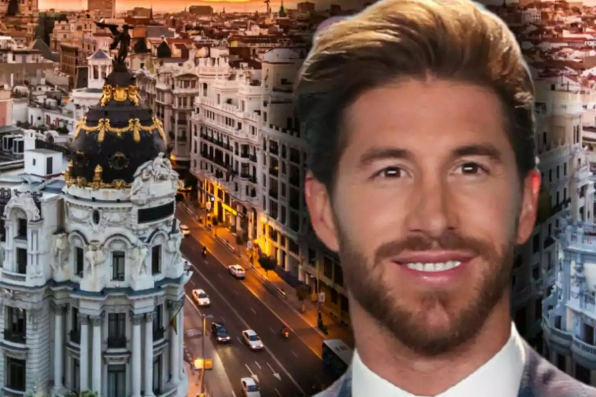 Sergio Ramos sonriente con barba y cabello castaño claro en primer plano con la Gran Vía de Madrid al fondo al atardecer