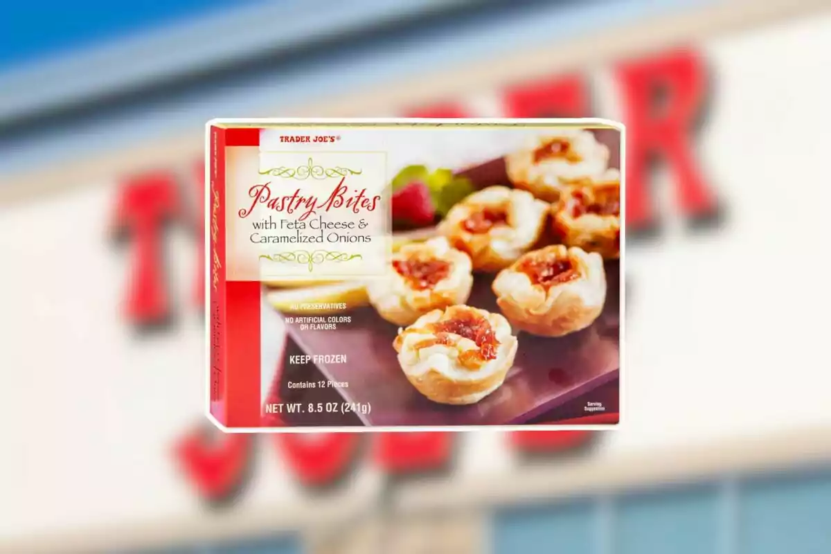 Caja de Pastry Bites con queso feta y cebolla caramelizada de Trader Joe’s sobre un fondo borroso del letrero de la tienda Caja de Pastry Bites con queso feta y cebolla caramelizada de Trader Joe’s sobre un fondo borroso del letrero de la tienda