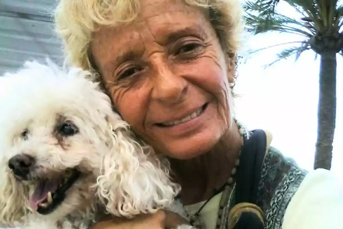 Imagen de Matilde Muñoz Cazorla, sonriente, con un perro blanco con la boca abierta