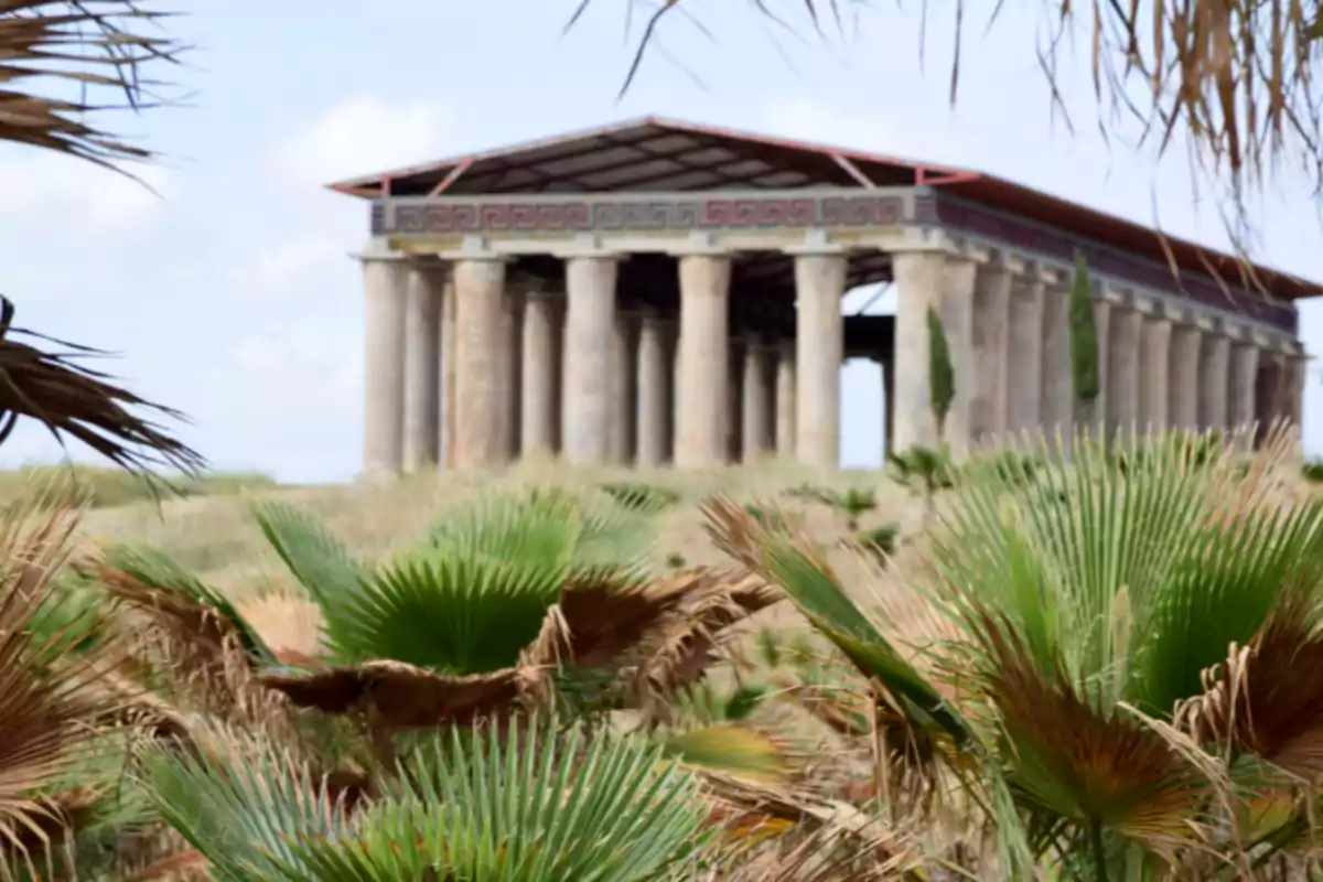 Templo antiguo de columnas rodeado de vegetación y palmas bajo un cielo parcialmente nublado Templo antiguo de columnas rodeado de vegetación y palmas bajo un cielo parcialmente nublado
