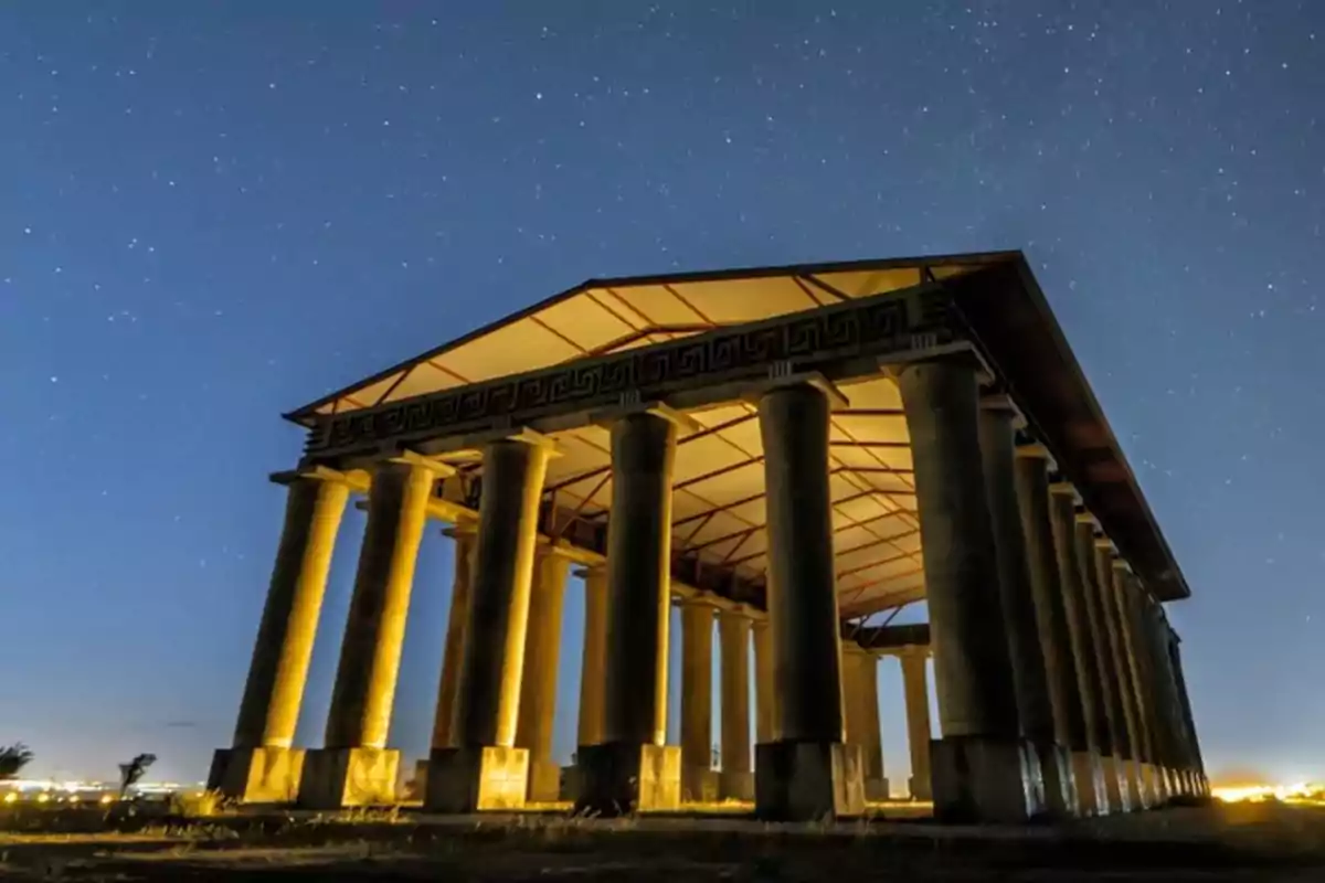 Templo con columnas iluminado por la noche bajo un cielo estrellado Templo con columnas iluminado por la noche bajo un cielo estrellado