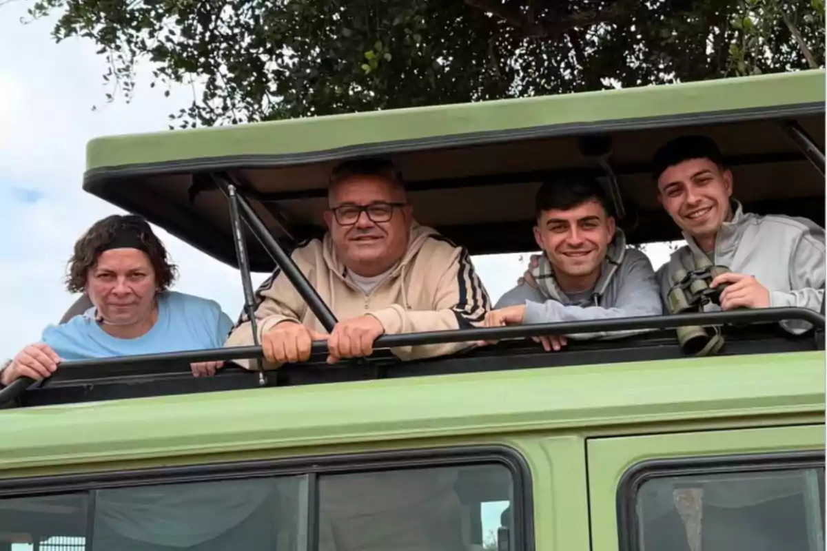 Pedri y su familia, Rosy, Fer y Fernando sonríen mientras asoman la cabeza por la ventana superior de un vehículo de safari verde, una de ellas sostiene unos binoculares y al fondo se ven ramas de un árbol. Pedri y su familia, Rosy, Fer y Fernando sonríen mientras asoman la cabeza por la ventana superior de un vehículo de safari verde, una de ellas sostiene unos binoculares y al fondo se ven ramas de un árbol.