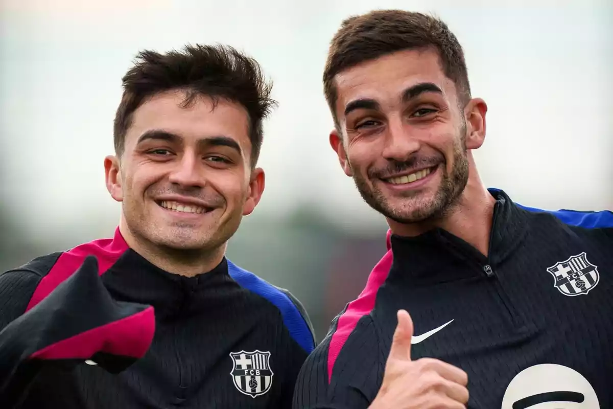 Dos jugadores del FC Barcelona sonríen y posan para la cámara durante un entrenamiento, ambos llevan chaquetas deportivas del equipo y uno de ellos hace el gesto de pulgar arriba Dos jugadores del FC Barcelona sonríen y posan para la cámara durante un entrenamiento, ambos llevan chaquetas deportivas del equipo y uno de ellos hace el gesto de pulgar arriba