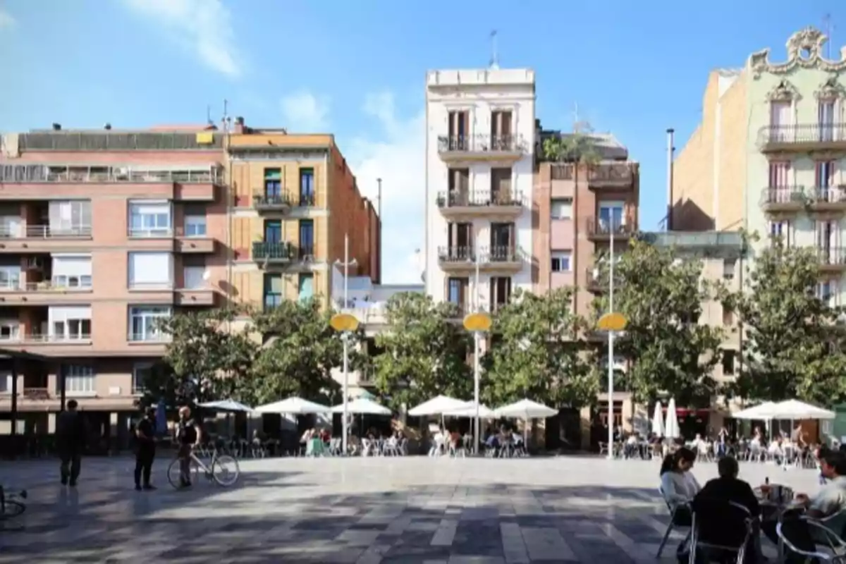 Plaza urbana con terrazas de cafeterías, árboles y edificios residenciales al fondo en un día soleado Plaza urbana con terrazas de cafeterías, árboles y edificios residenciales al fondo en un día soleado
