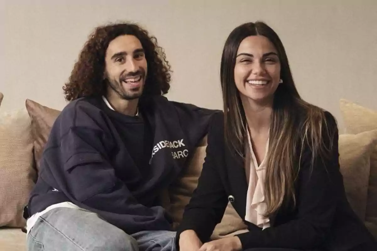 Marc Cucurella y Claudia Rodríguez sentadas en un sofá sonríen mientras miran a la cámara Marc Cucurella y Claudia Rodríguez sentadas en un sofá sonríen mientras miran a la cámara