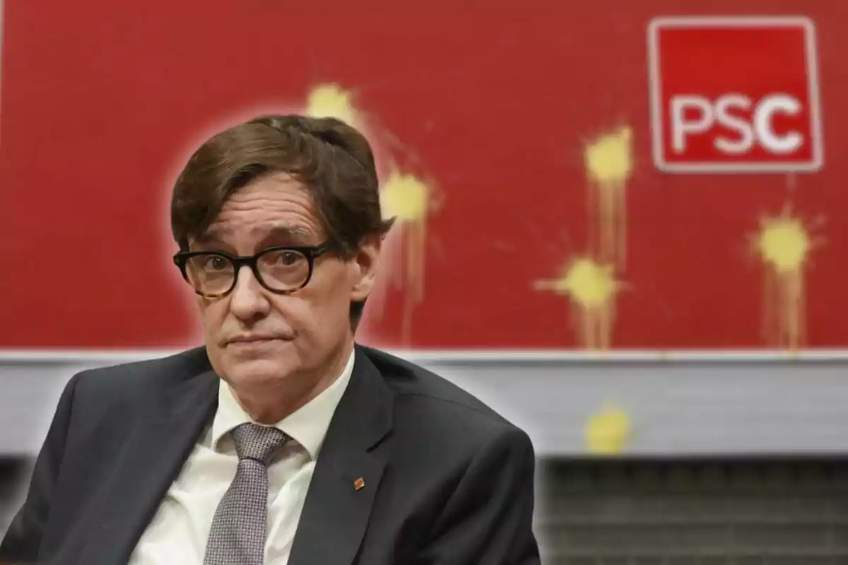 Hombre con gafas y traje sentado frente a un fondo rojo con el logo de PSC y manchas amarillas