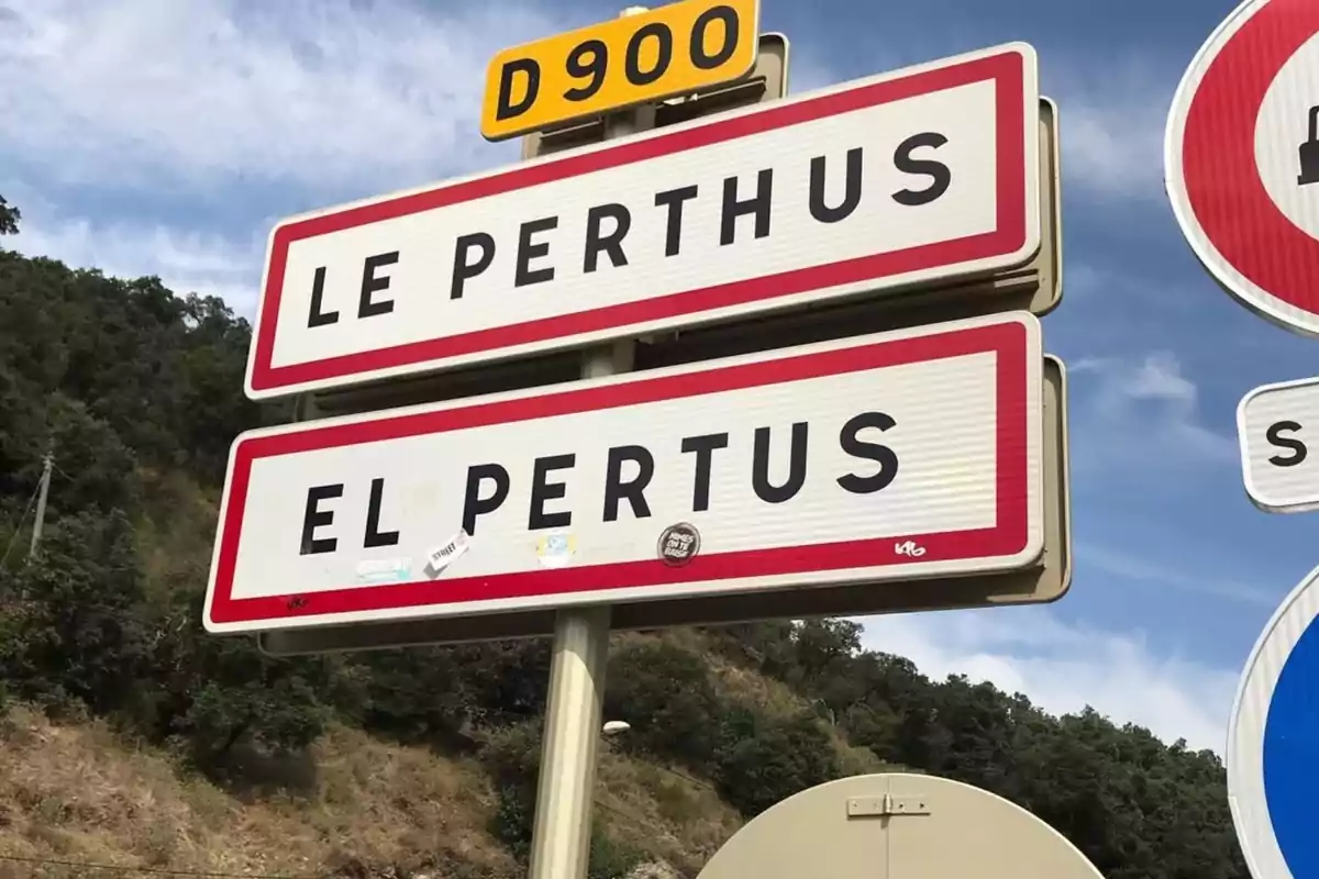 Cartells d’entrada a la localitat fronterera de Le Perthus en francès i El Pertus en català amb fons de cel i vegetació. Cartells d’entrada a la localitat fronterera de Le Perthus en francès i El Pertus en català amb fons de cel i vegetació.