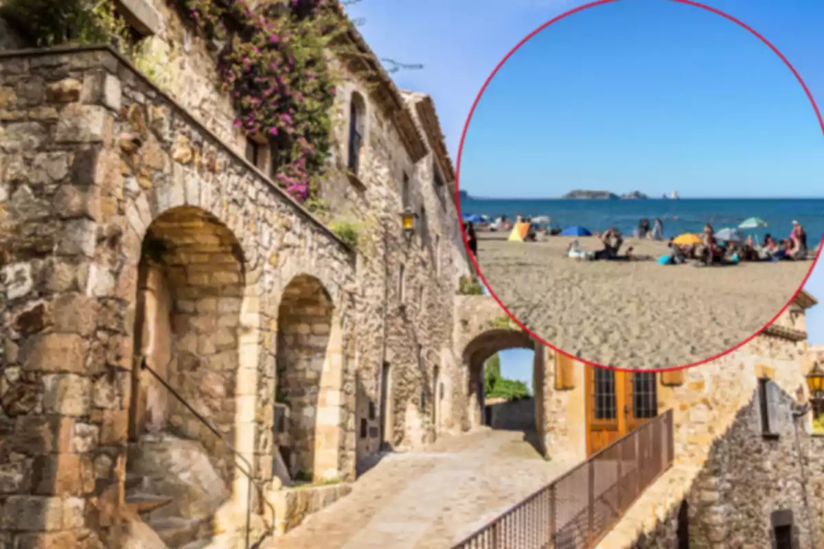 Calle empedrada con casas de piedra y arcos, flores moradas en la fachada y un círculo que muestra una playa con personas y sombrillas frente al mar
