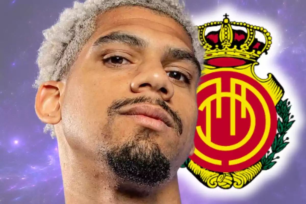 Hombre de cabello rizado y barba con el escudo del club Mallorca de fondo