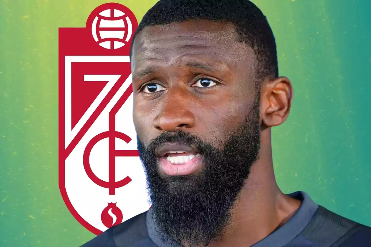 Futbolista de barba y cabello corto con el escudo del Granada CF de fondo