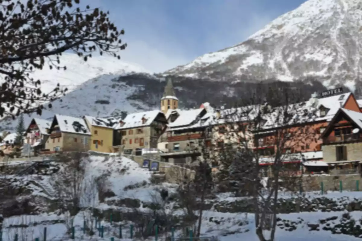 Pueblo de montaña con casas y tejados cubiertos de nieve rodeado de montañas nevadas en un día despejado Pueblo de montaña con casas y tejados cubiertos de nieve rodeado de montañas nevadas en un día despejado