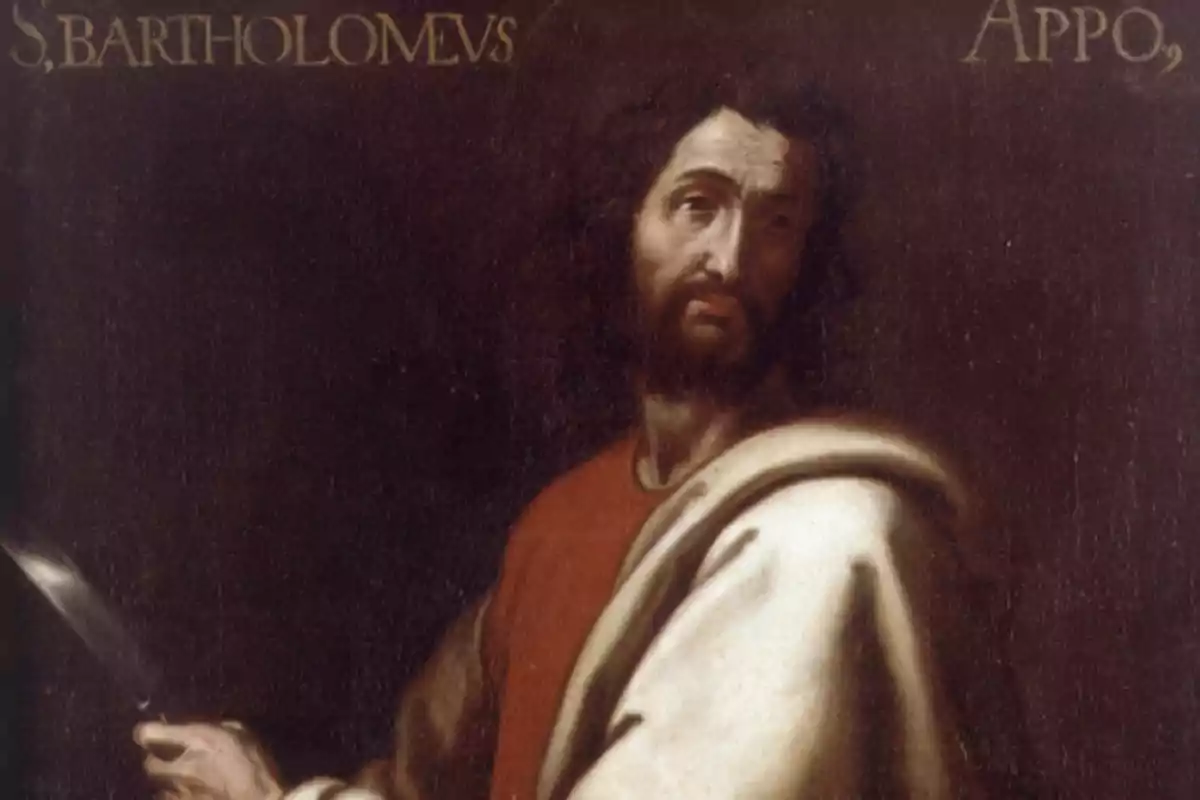Pintura d’un home amb barba i cabell fosc que sosté un ganivet i porta una túnica clara sobre una peça vermella amb fons fosc i lletres daurades a la part superior Pintura d’un home amb barba i cabell fosc que sosté un ganivet i porta una túnica clara sobre una peça vermella amb fons fosc i lletres daurades a la part superior