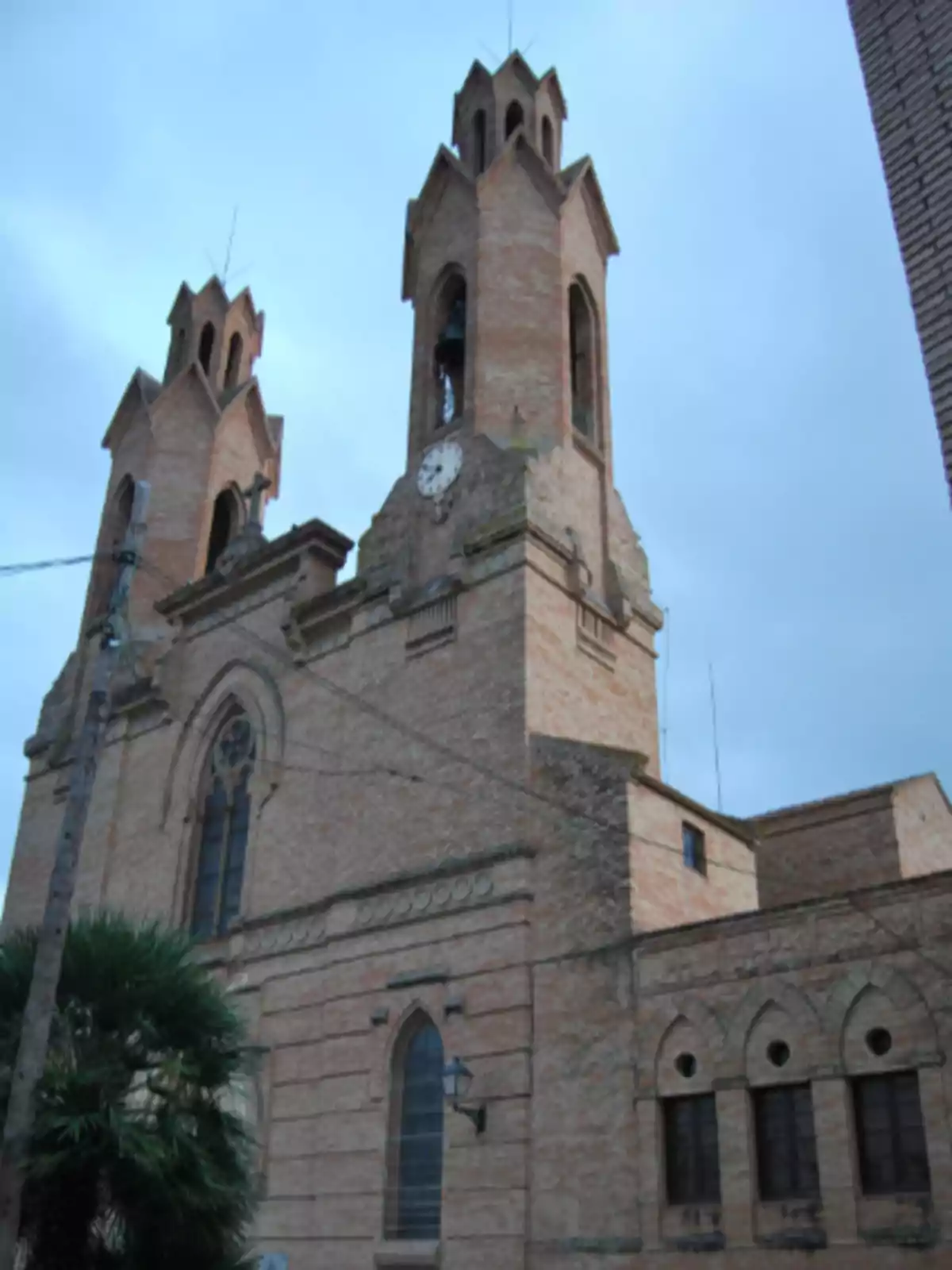 Iglesia de ladrillo con dos torres y un reloj en la fachada bajo un cielo nublado Iglesia de ladrillo con dos torres y un reloj en la fachada bajo un cielo nublado