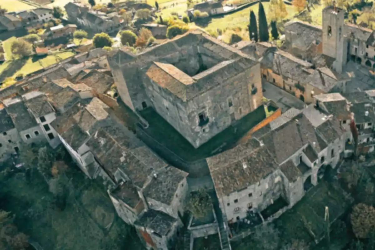 Vista aèria d’un castell medieval envoltat de cases de pedra amb teulades de teula en un petit poble europeu Vista aèria d’un castell medieval envoltat de cases de pedra amb teulades de teula en un petit poble europeu