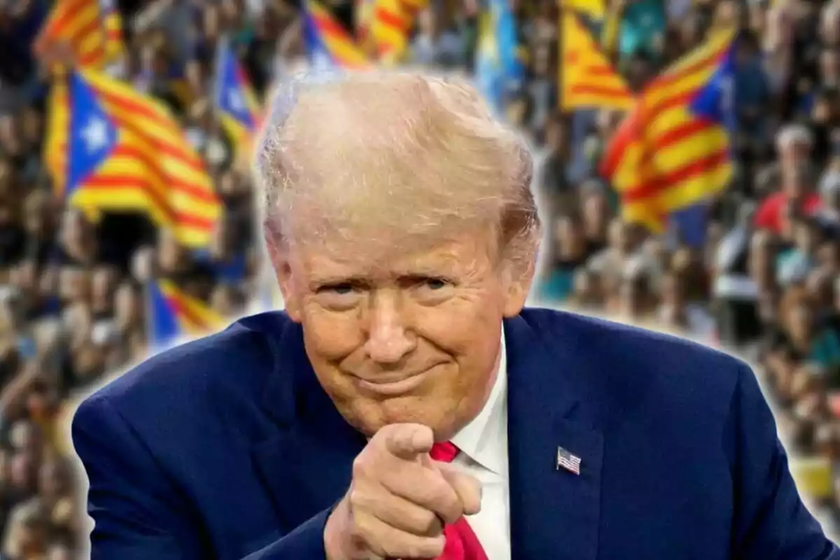 Un hombre de cabello rubio y traje azul señala hacia la cámara con una multitud al fondo ondeando banderas esteladas.