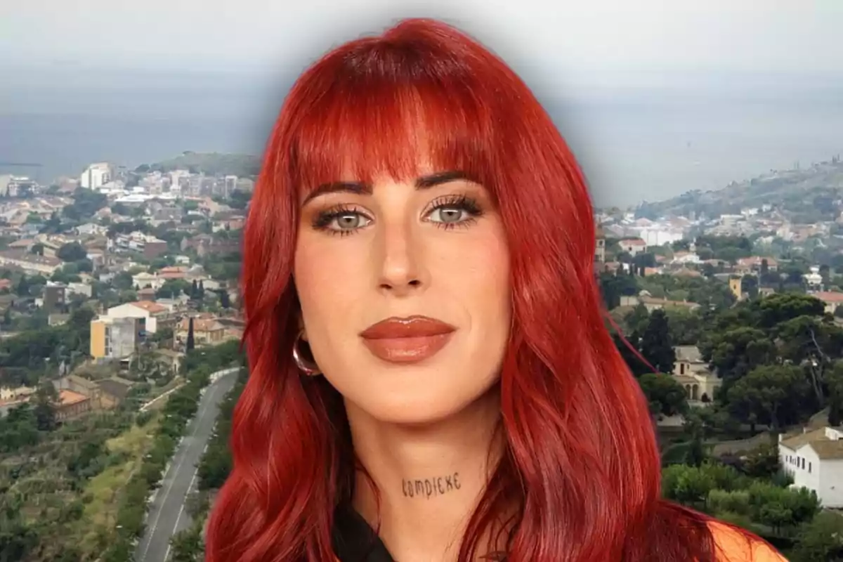 Mujer de cabello largo y rojo con flequillo, labios maquillados y tatuaje en el cuello, posando frente a un paisaje urbano con vegetación y edificios al fondo