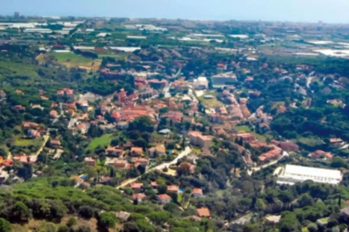 Vista aérea de un pueblo rodeado de vegetación y campos verdes en un día soleado Vista aérea de un pueblo rodeado de vegetación y campos verdes en un día soleado