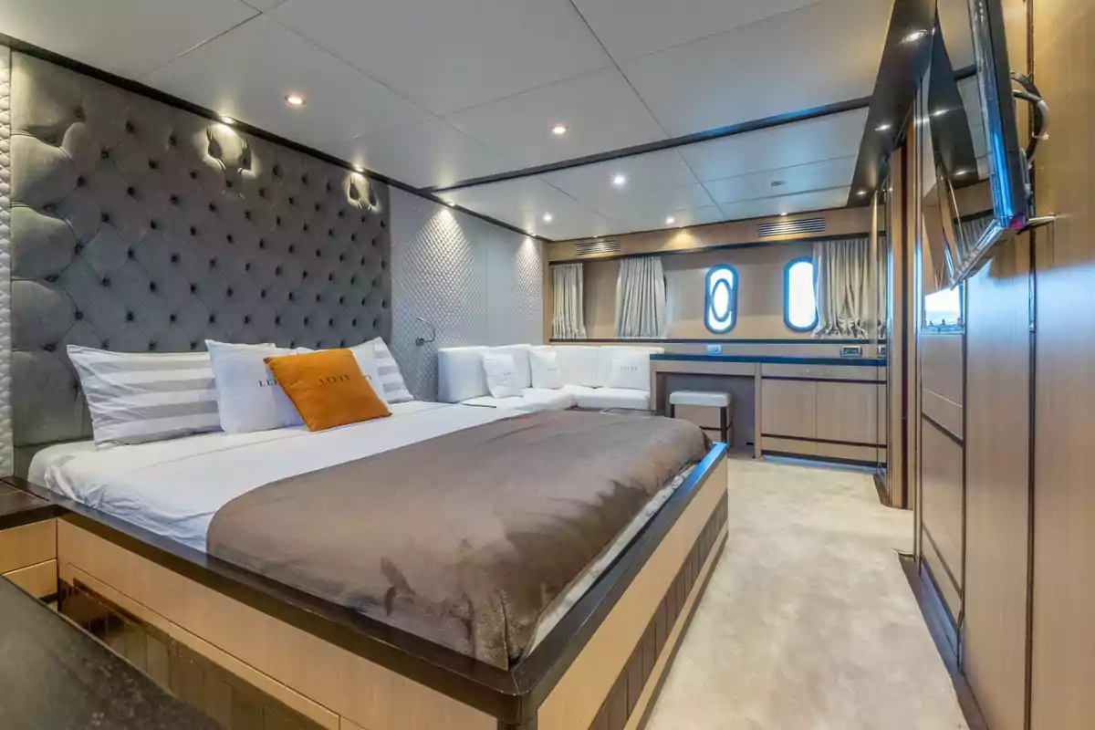 Habitación moderna y lujosa con cama grande, cabecera acolchada, sofá blanco, escritorio, ventanas redondas y decoración en tonos neutros del yate Lefty Habitación moderna y lujosa con cama grande, cabecera acolchada, sofá blanco, escritorio, ventanas redondas y decoración en tonos neutros del yate Lefty