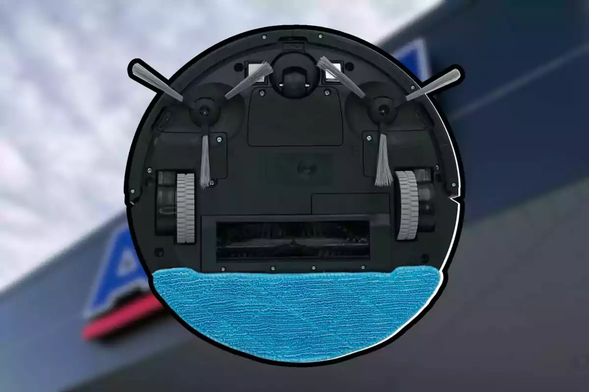 Vista inferior d’un robot aspirador amb raspalls laterals, rodes i una mopa blava sobre un fons desenfocat