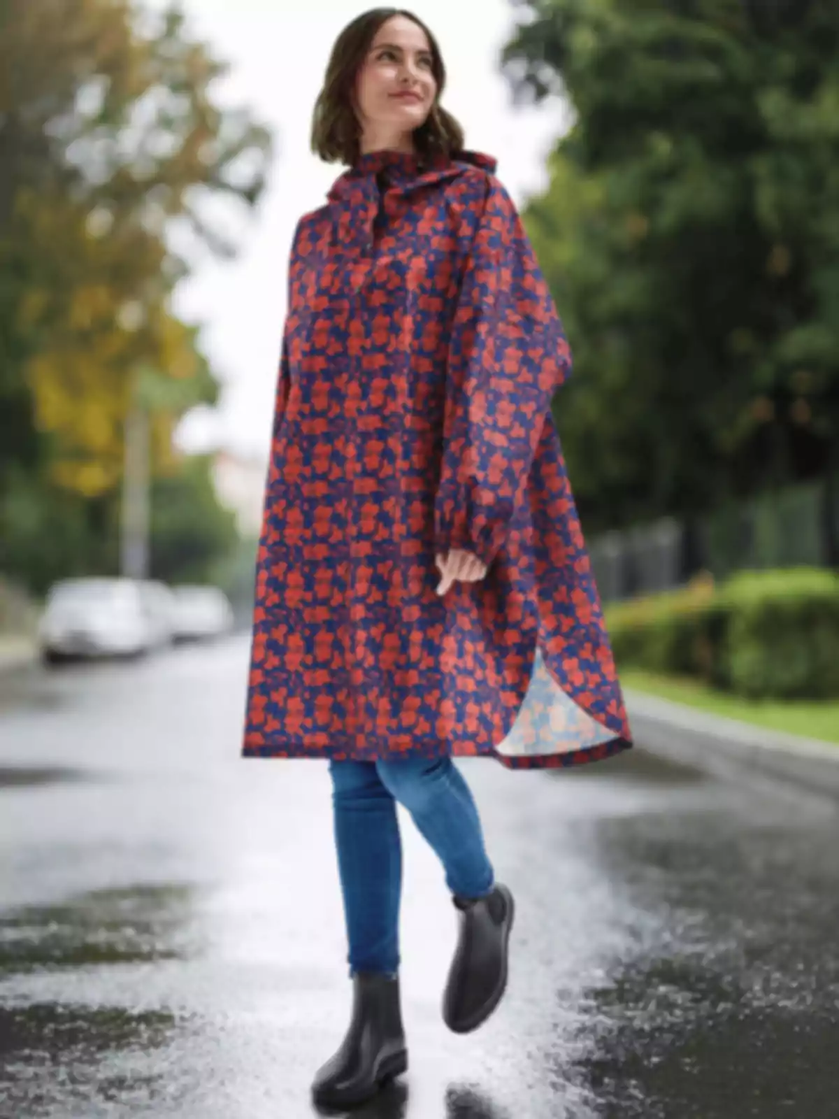 Mujer caminando por una calle mojada vistiendo un impermeable colorido y botas negras Mujer caminando por una calle mojada vistiendo un impermeable colorido y botas negras