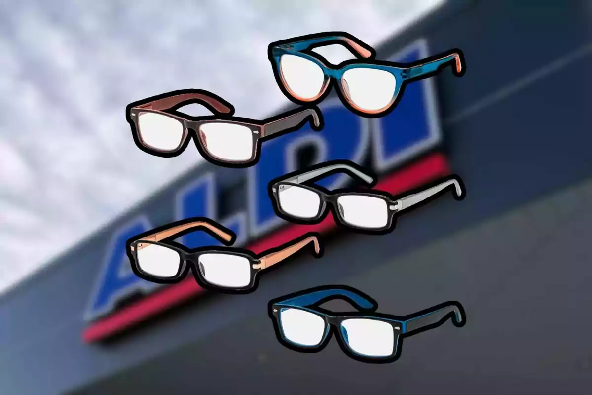 Cinco pares de gafas de diferentes colores flotan frente a un letrero borroso de una tienda