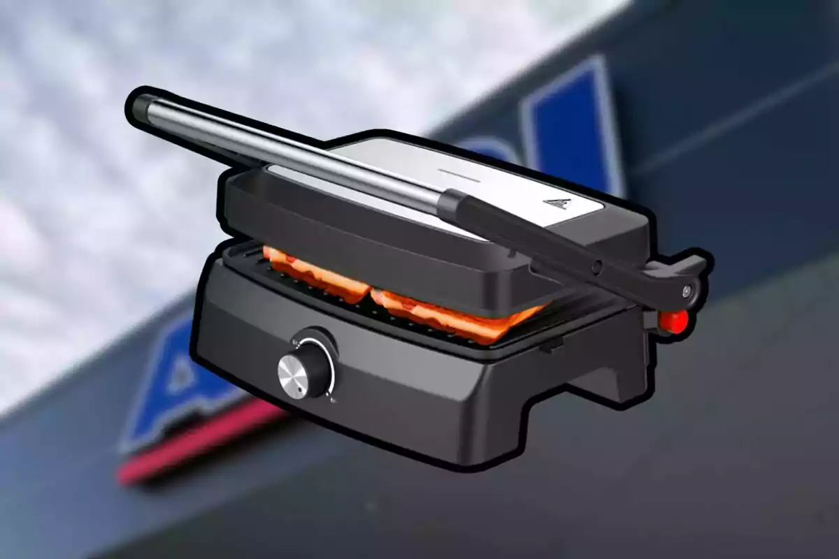 Parrilla eléctrica negra con perilla plateada y dos sándwiches en su interior sobre un fondo desenfocado de una tienda Parrilla eléctrica negra con perilla plateada y dos sándwiches en su interior sobre un fondo desenfocado de una tienda