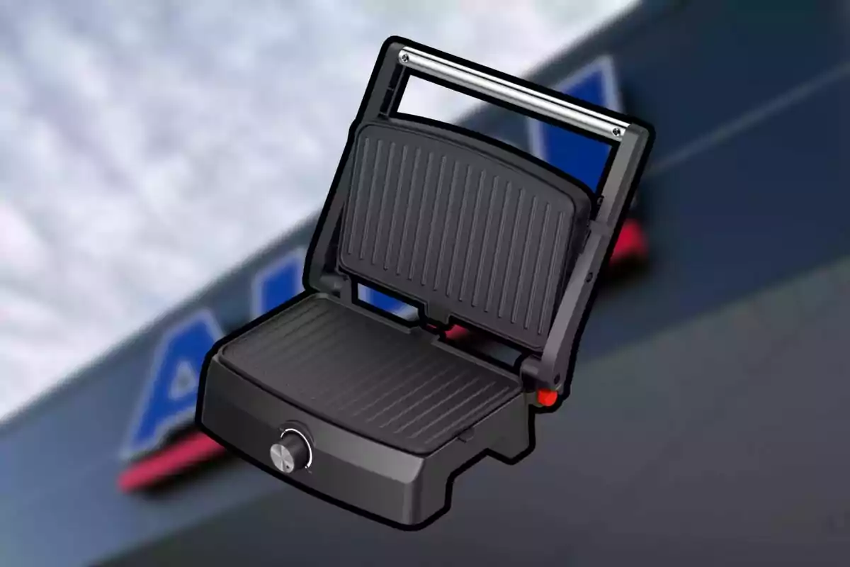 Parrilla eléctrica negra de placas acanaladas abierta con fondo desenfocado de un edificio Parrilla eléctrica negra de placas acanaladas abierta con fondo desenfocado de un edificio