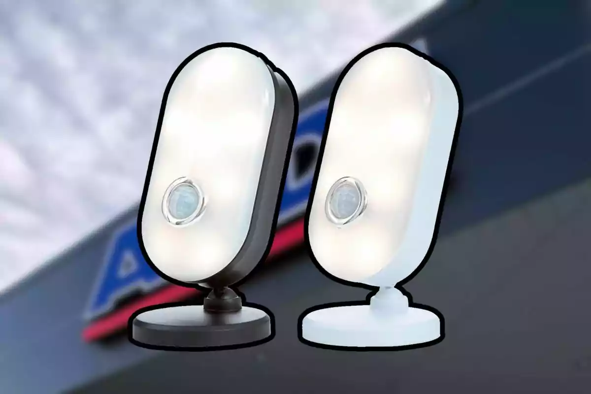 Dos lámparas LED con sensor de movimiento, una de color negro y otra blanca, sobre un fondo desenfocado de una tienda. Dos lámparas LED con sensor de movimiento, una de color negro y otra blanca, sobre un fondo desenfocado de una tienda.