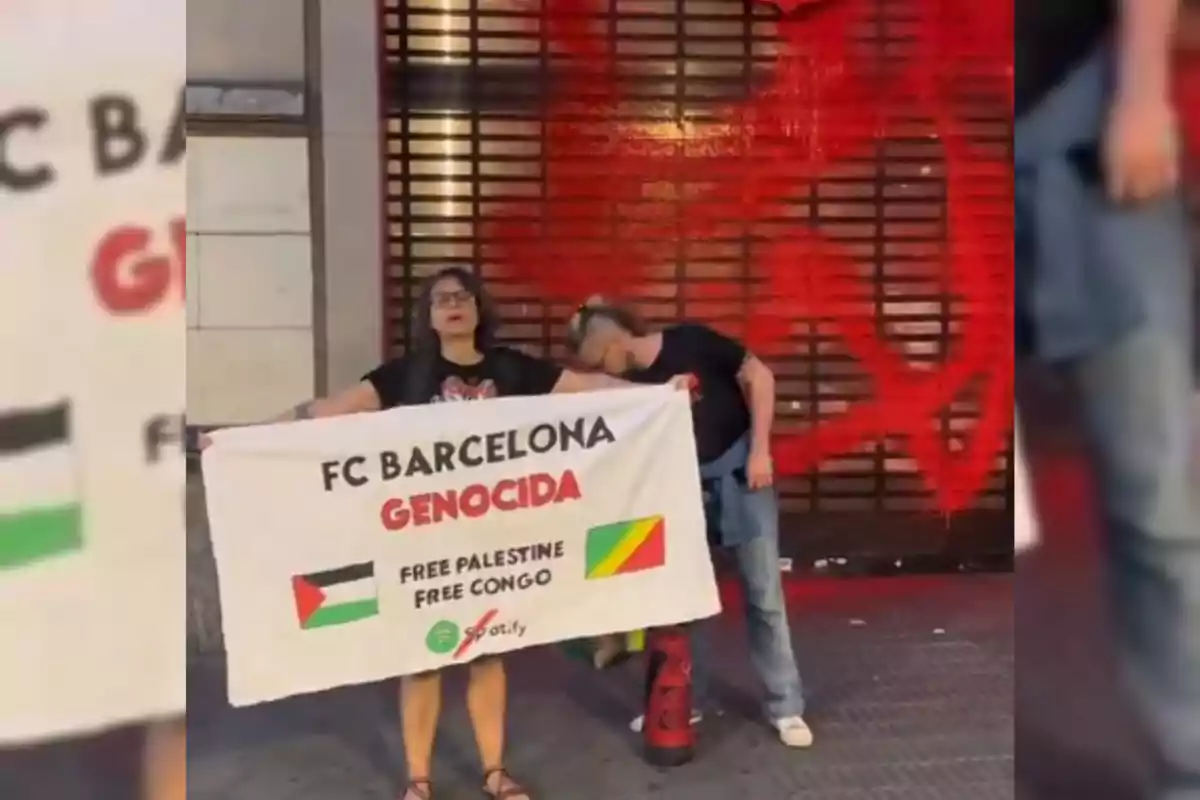 Dues persones sostenen una pancarta que critica el FC Barcelona i demana l’alliberament de Palestina i el Congo, amb una cortina metàl·lica i grafit vermell de fons.