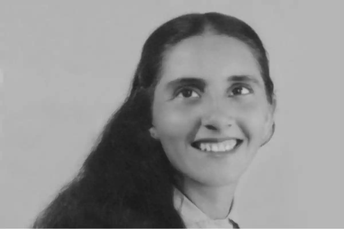 Mujer joven de cabello largo y oscuro sonriendo en una fotografía en blanco y negro
