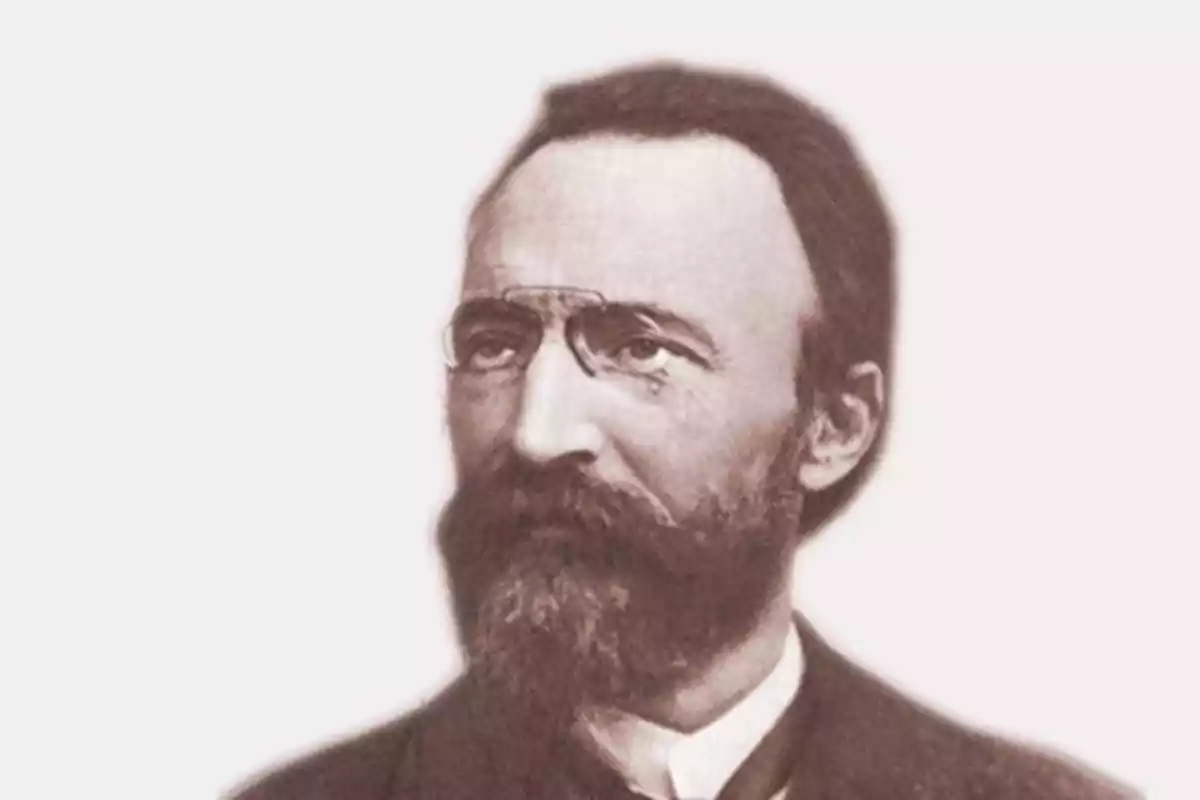 Retrato antiguo de un hombre con barba y bigote usando gafas pequeñas sobre la frente