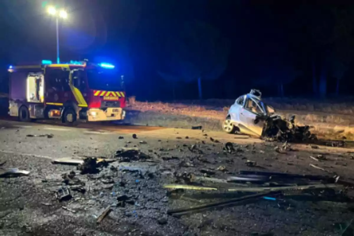 Un camió de bombers il·luminat atén un accident nocturn en una carretera a Traspinedo (Valladolid) on un cotxe està greument danyat i hi ha runa escampada per l’asfalt.