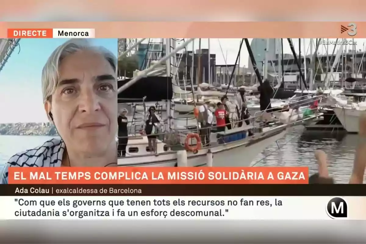 Captura de pantalla d’una transmissió en directe des de Menorca que mostra una dona amb auriculars en primer pla i, al fons, un grup de persones en una barca al port, amb un titular que informa sobre complicacions en una missió solidària a Gaza a causa del mal temps.