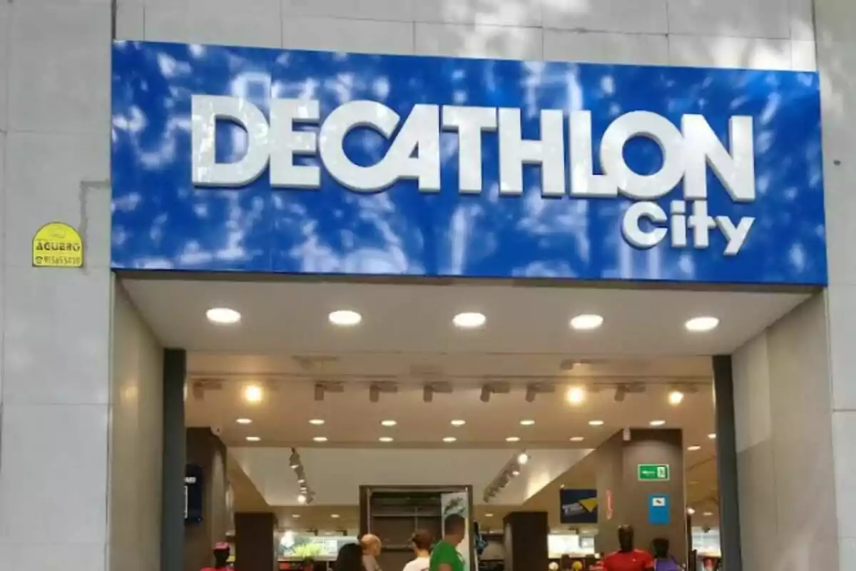 Entrada de una tienda Decathlon City con el letrero azul y blanco y varias personas entrando al establecimiento.