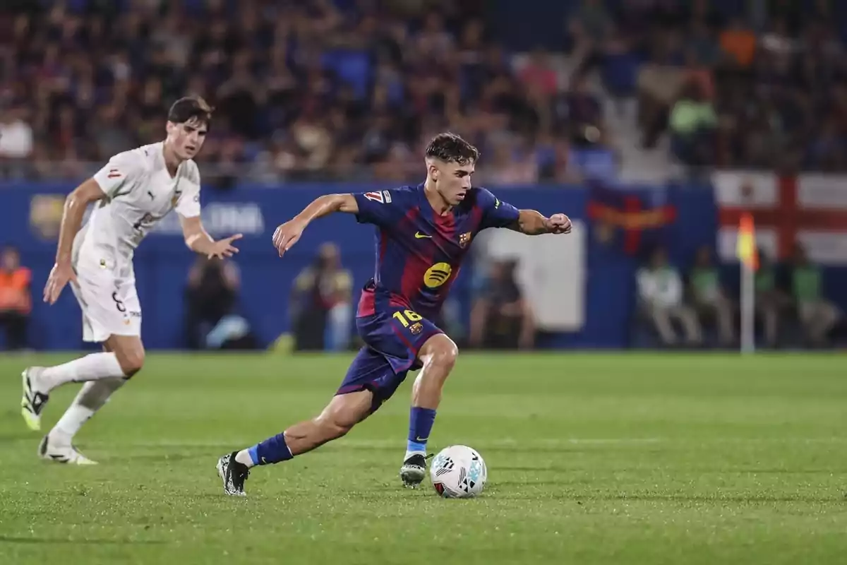 Jugador del Barcelona controla la pilota durant un partit mentre un rival el persegueix al camp de futbol. Jugador del Barcelona controla la pilota durant un partit mentre un rival el persegueix al camp de futbol.