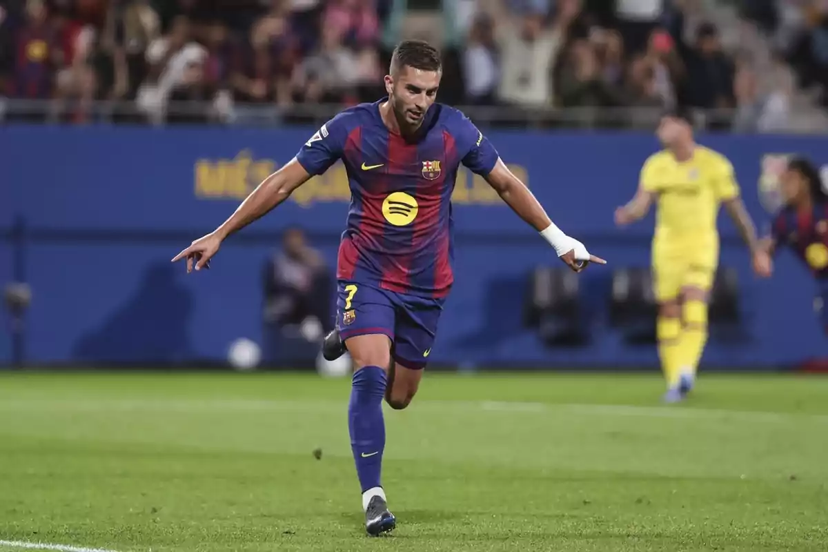 Futbolista del Barcelona celebrant un gol al camp amb els braços estesos i aficionats de fons