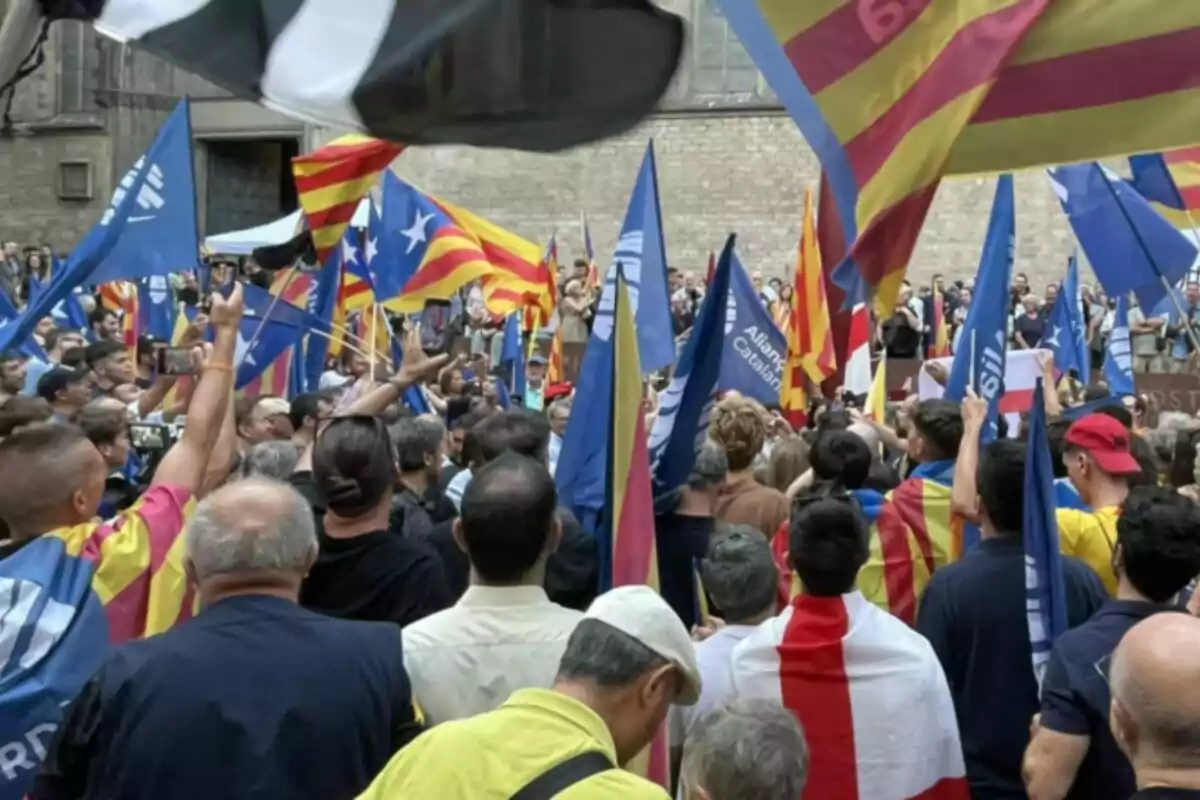 Multitud de personas reunidas en una manifestación con banderas catalanas y banderas azules ondeando en el aire