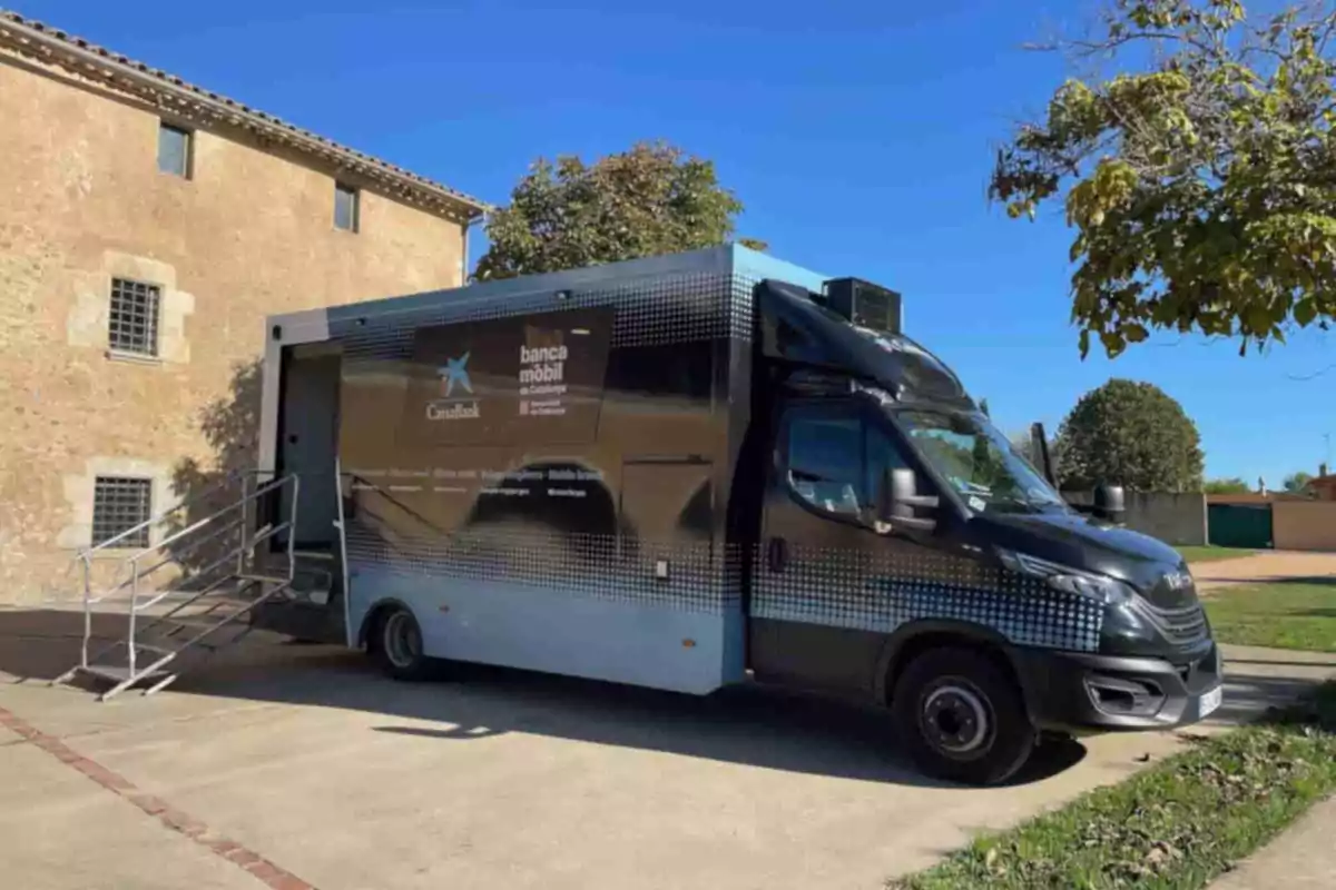 Camió de banca mòbil estacionat al costat d’un edifici de pedra en un dia assolellat