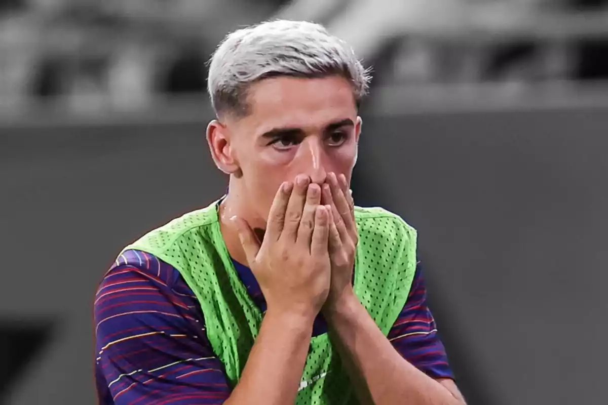 Young player with bleached blonde hair covering his mouth with both hands and an expression of surprise or concern Young player with bleached blonde hair covering his mouth with both hands and an expression of surprise or concern