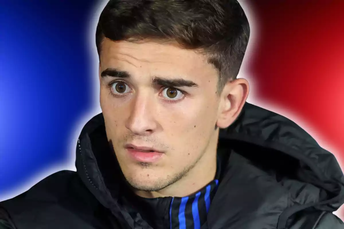 Young man in a black jacket looking straight ahead with a serious expression and a blue and red gradient background