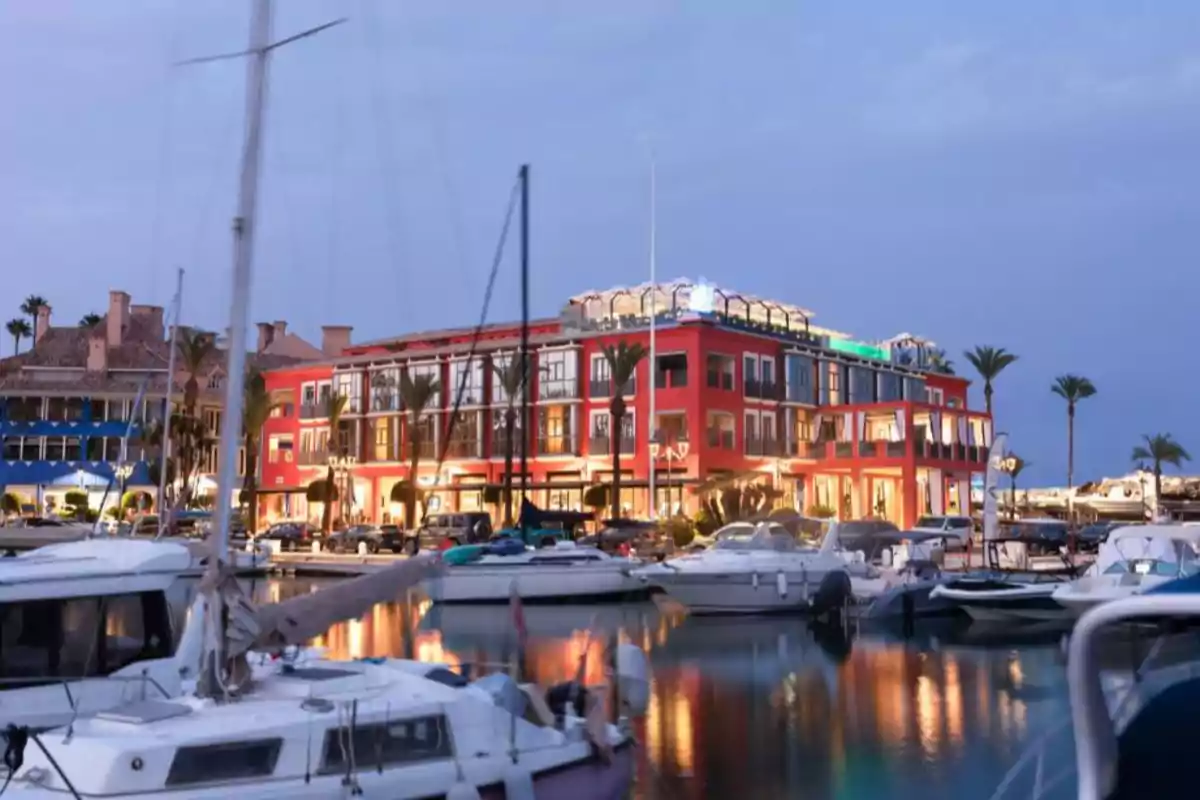 Hotel MIM Sotogrande de Leo Messi, il·luminat al capvespre al costat d’un port amb diversos iots i palmeres Hotel MIM Sotogrande de Leo Messi, il·luminat al capvespre al costat d’un port amb diversos iots i palmeres