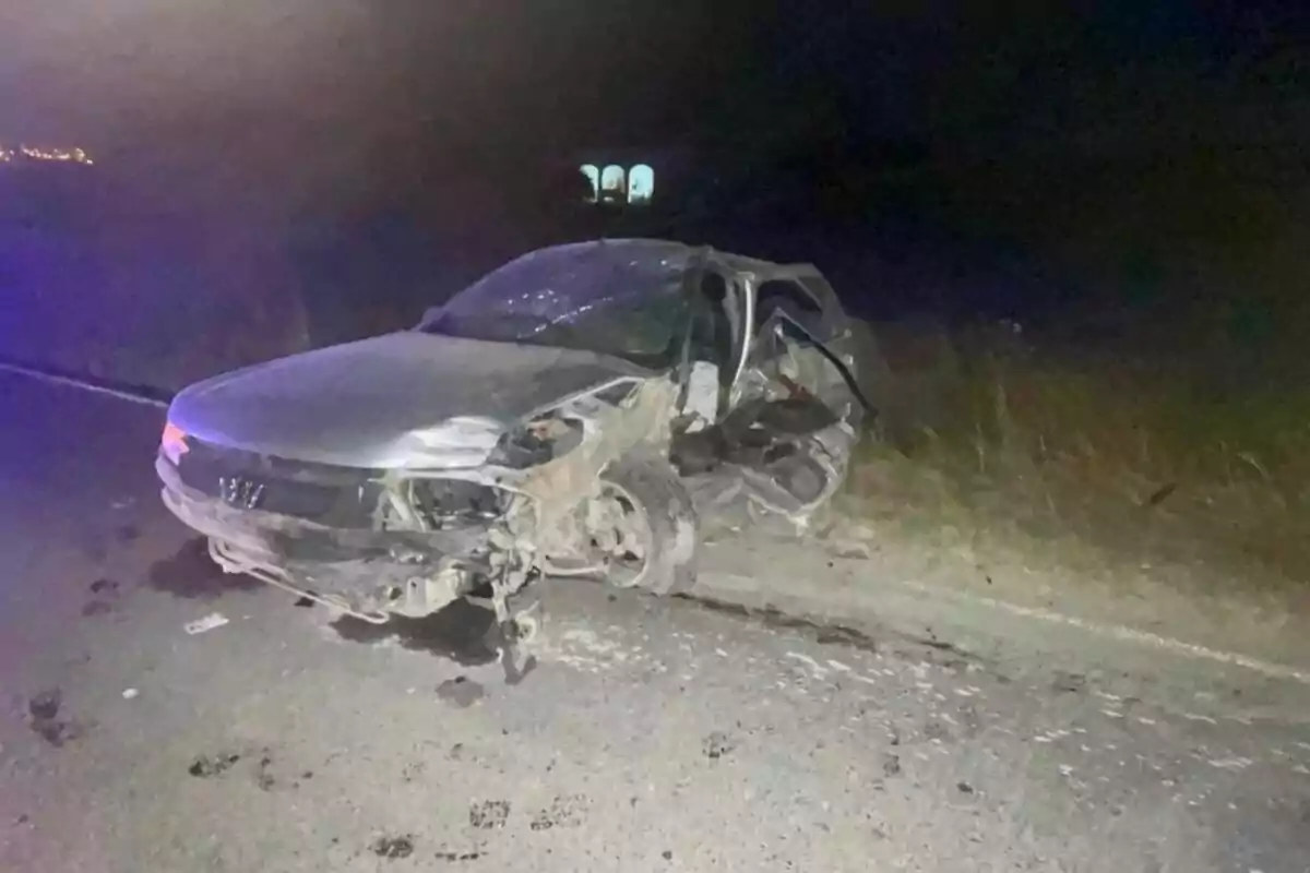 Cotxe gris amb greus danys després d’un accident en una carretera durant la nit