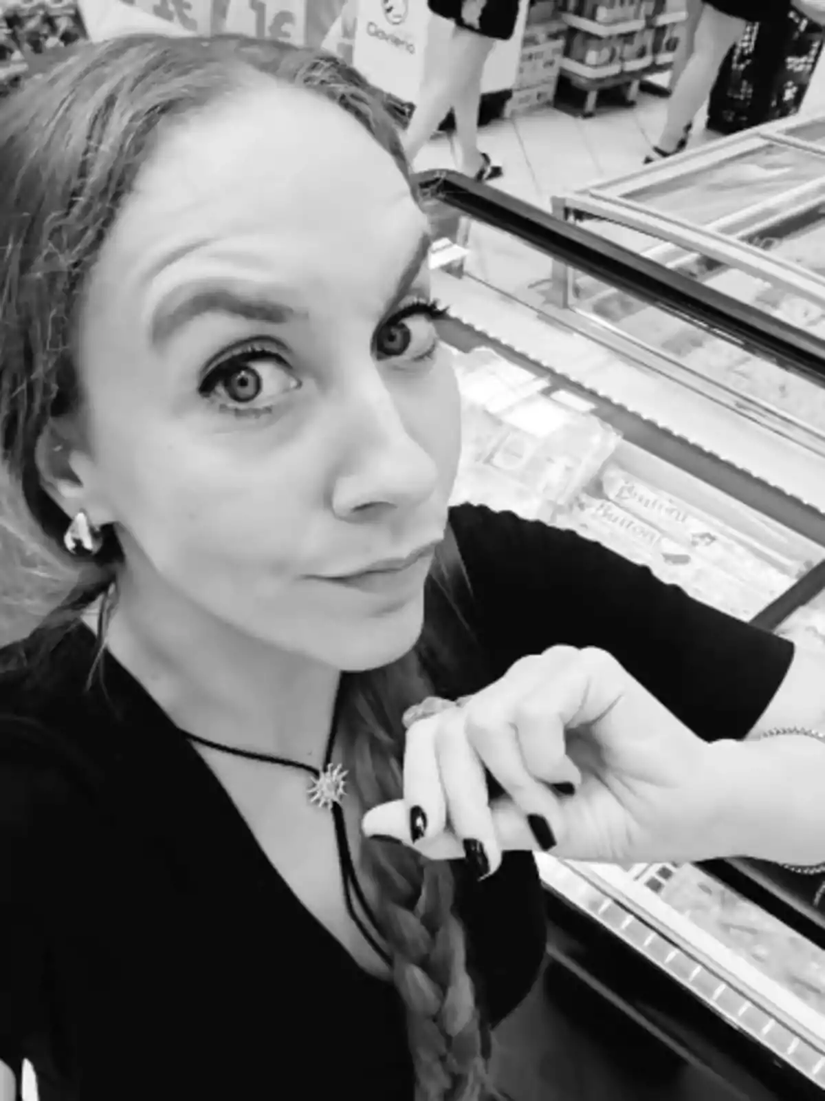 Iris Soler amb una trena llarga i un collaret de sol fent-se una selfie en un supermercat d’Alcampo davant de vitrines de congelats