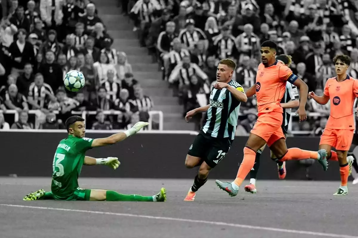 Un porter vestit de verd intenta aturar una pilota mentre un jugador amb uniforme de ratlles negres i blanques i diversos jugadors amb uniforme taronja corren a l'àrea durant un partit de futbol amb el públic de fons en blanc i negre. Un porter vestit de verd intenta aturar una pilota mentre un jugador amb uniforme de ratlles negres i blanques i diversos jugadors amb uniforme taronja corren a l'àrea durant un partit de futbol amb el públic de fons en blanc i negre.